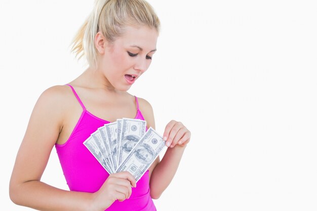 Young casual woman with fanned us banknotes