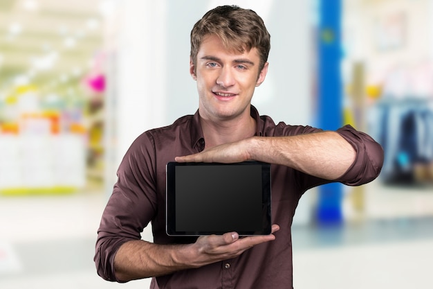 Young casually dressed man showing blank dark digital tablet screen