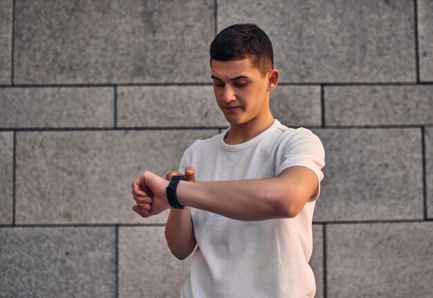 A young Caucasian American guy looks puzzled at his watch on his hand somewhere late