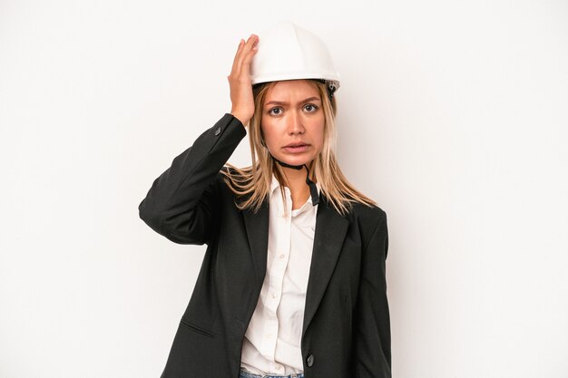 Young caucasian architect woman wearing a helmet isolated on white background being shocked, she has remembered important meeting.