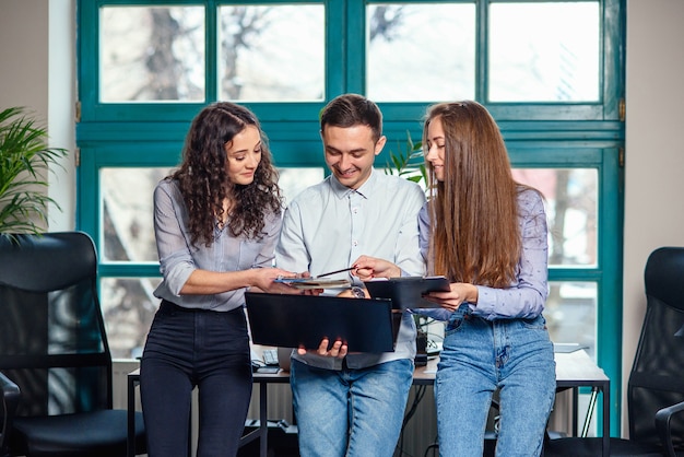 Young caucasian architects or designers using color palette for new project on the laptop in the stylish modern office with big window.