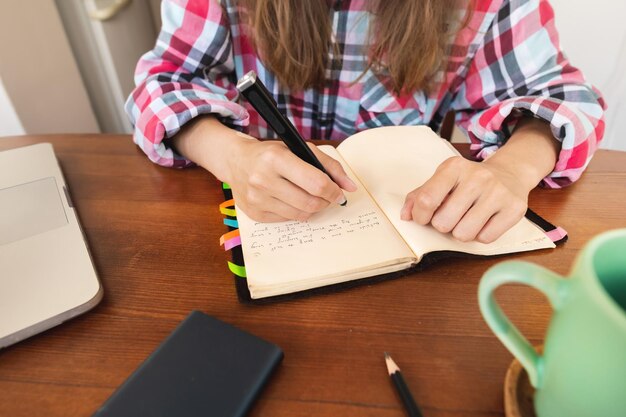 Photo young caucasian attractive woman taking notes in her notebook while sitting