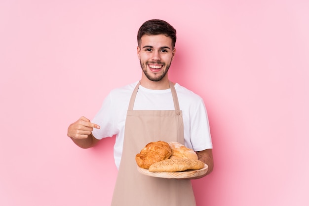 Persona isolata giovane uomo caucasico del panettiere che indica a mano uno spazio della copia della camicia, fiero e sicuro