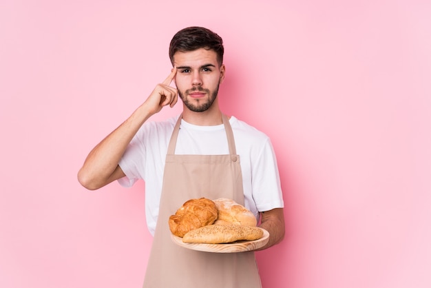 Young caucasian baker man isolated pointing temple with finger, thinking, focused on a task.