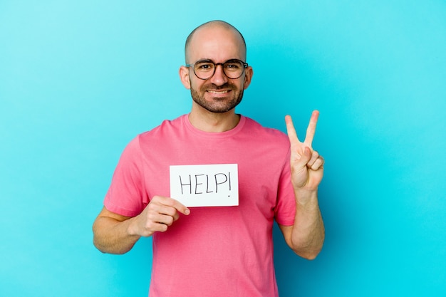 Young caucasian bald man holding a Help placard isolated on purple background showing number two with fingers.