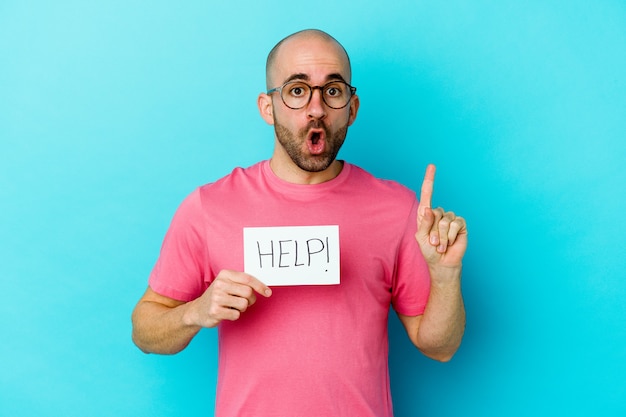 Young caucasian bald man holding a Help placard isolated on purple wall having some great idea