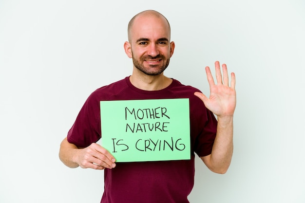 Young caucasian bald man holding a Mother Nature crying isolated on white background smiling cheerful showing number five with fingers.