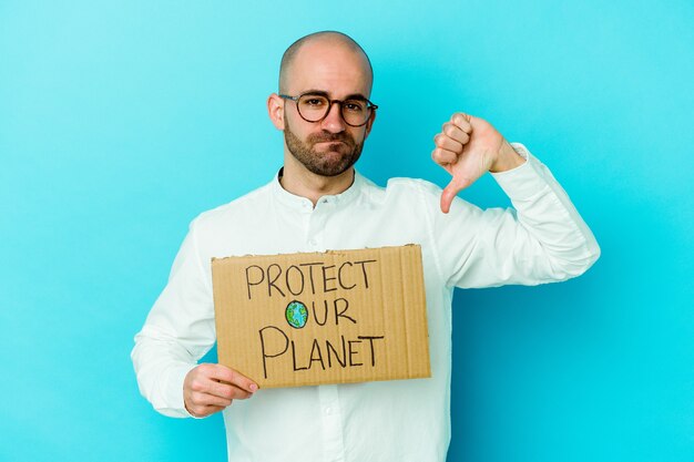 Young caucasian bald man holding a protect our planet placard isolated on purple wall showing a dislike gesture, thumbs down. Disagreement concept.