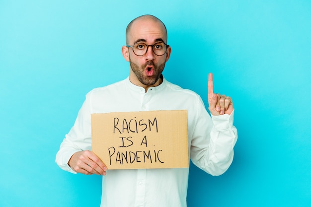 Young caucasian bald man holding a racism is a pandemic isolated on white wall having some great idea, concept of creativity.