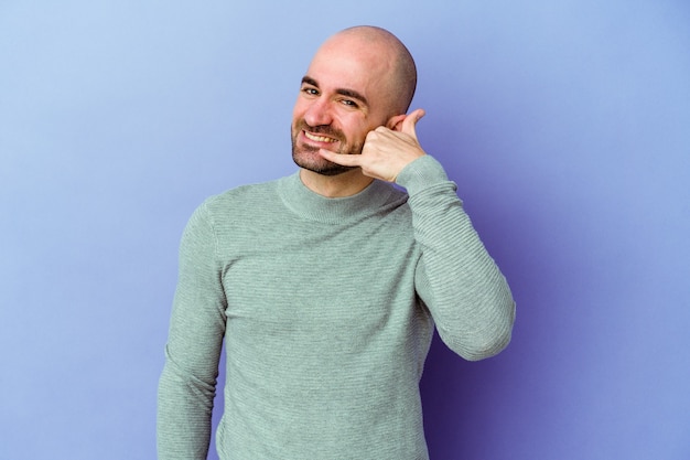 Young caucasian bald man isolated on purple background showing a mobile phone call gesture with fingers.