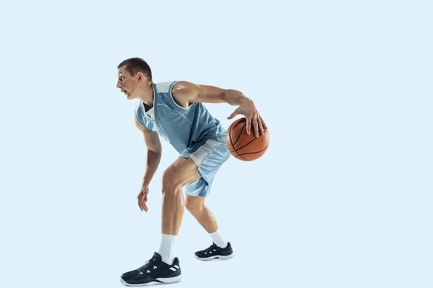 Young caucasian basketball player against white studio background