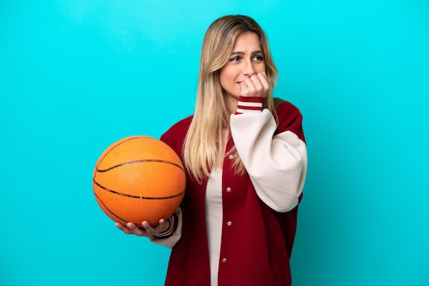 Young caucasian basketball player woman isolated on blue background having doubts