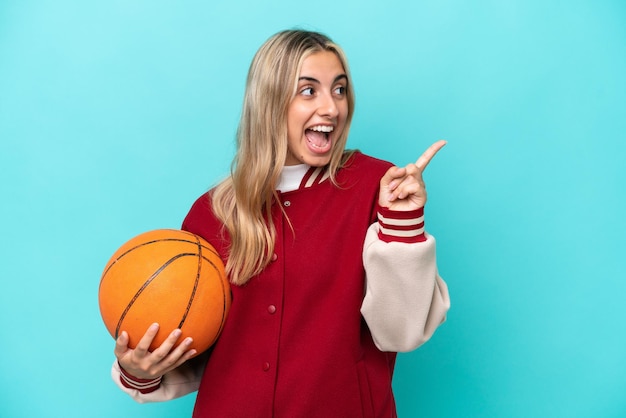 Young caucasian basketball player woman isolated on blue background intending to realizes the solution while lifting a finger up