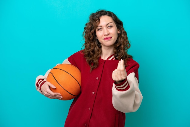 Foto giovane donna caucasica del giocatore di basket isolata su sfondo blu che fa gesto di denaro