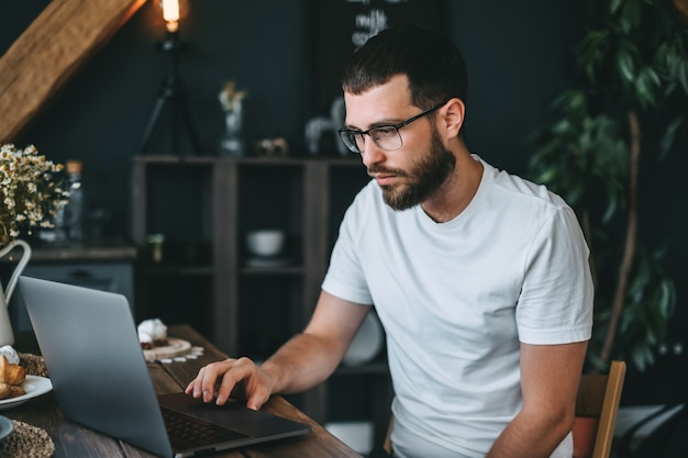 Young caucasian bearded man freelancer using laptop computer, work at home.