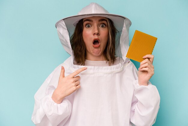 Young caucasian beekeeper woman isolated on blue background