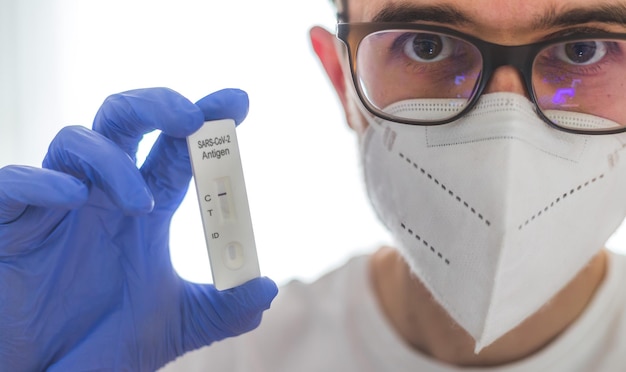 Photo young caucasian biologist or pharmacist is holding a covid19 or corona antigen test