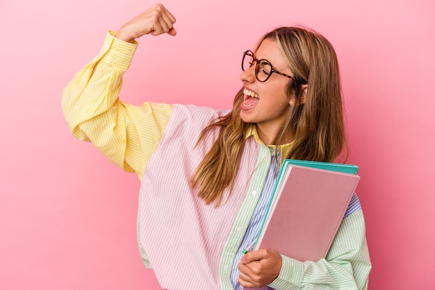 勝利の後に拳を上げて孤立した本を保持している若い白人金髪学生女性