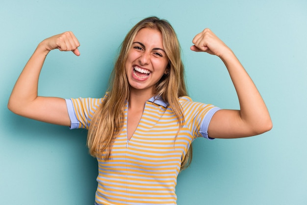 Young caucasian blonde woman isolated on blue background  cheering carefree and excited. Victory concept.