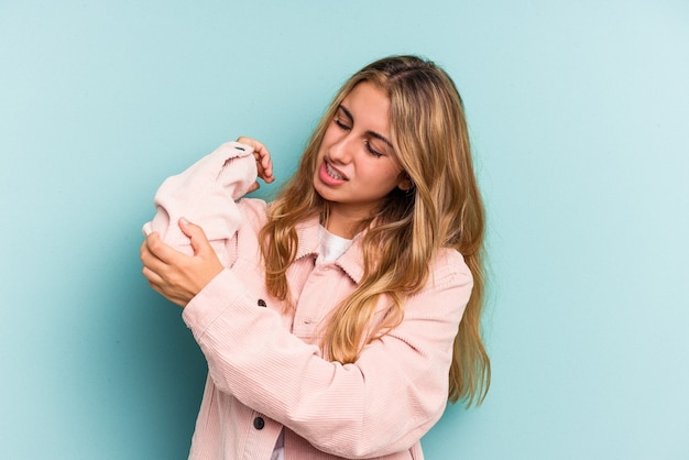 Young caucasian blonde woman isolated on blue background  massaging elbow, suffering after a bad movement.