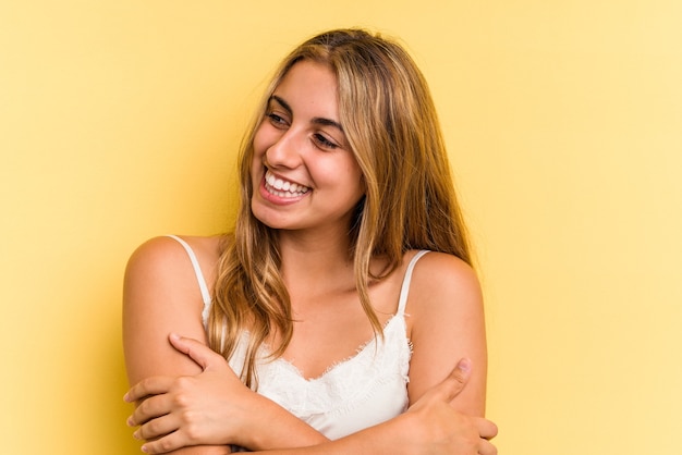 Young caucasian blonde woman isolated on yellow background  smiling confident with crossed arms.