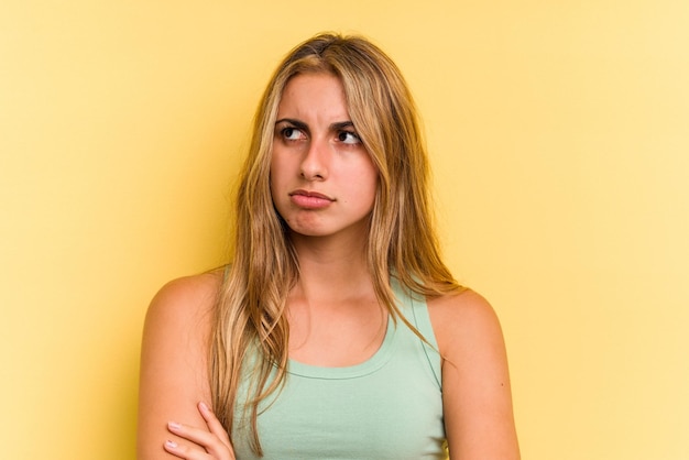 Young caucasian blonde woman isolated on yellow background  tired of a repetitive task.