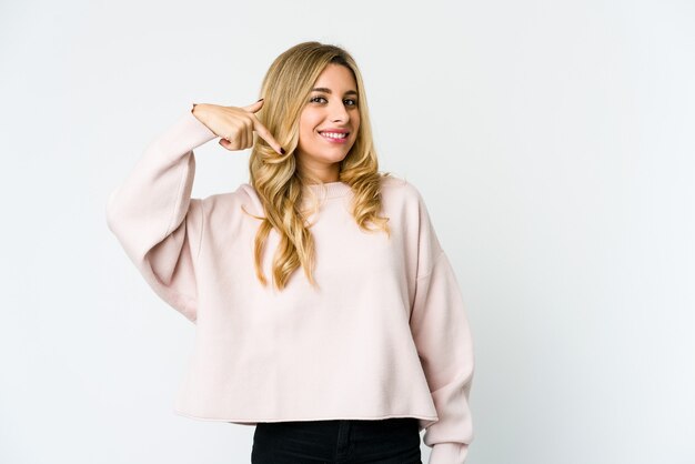 Young caucasian blonde woman person pointing by hand to a shirt copy space, proud and confident