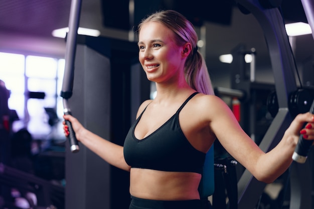 Young caucasian blonde woman training her arms in a gym