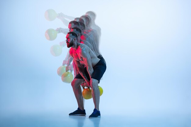 Young caucasian bodybuilder training over blue background