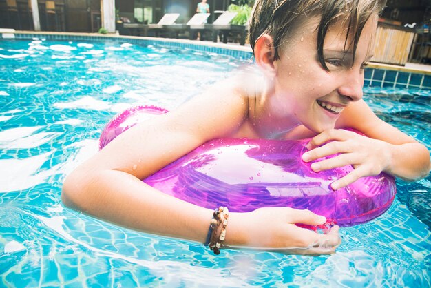 Young caucasian boy enjoying floating in the pool with tube