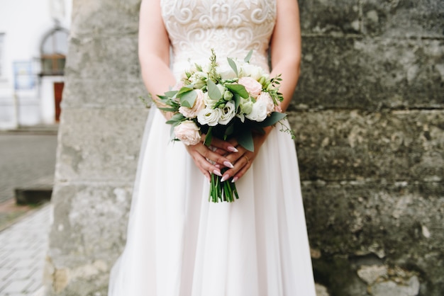 Young caucasian bride holding her wedding bouquet in front of her on her wedding day