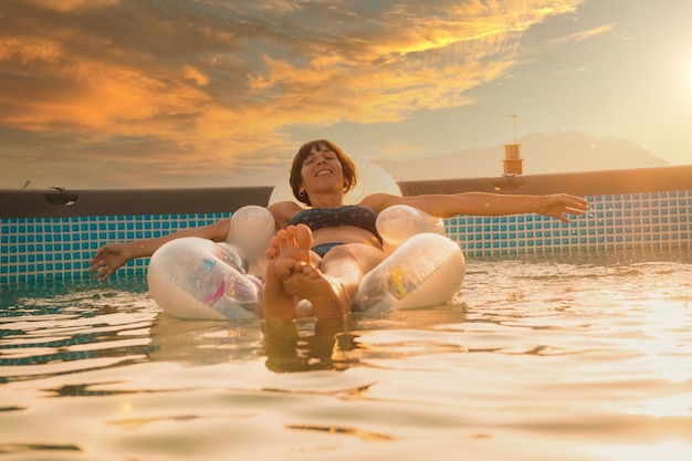 A young Caucasian brunette enjoying the summer on a mat in the pool