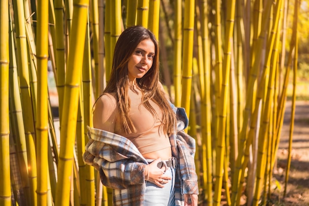 Young Caucasian brunette girl in a plaid wool sweater in a bamboo forest