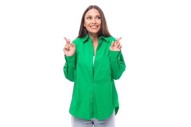 Young caucasian brunette lady with makeup dressed in an elegant green shirt points with her hands