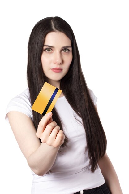 垂直のモックアップのための金の銀行のクレジットカードを保持している白いTシャツの若い白人ブルネットの女性