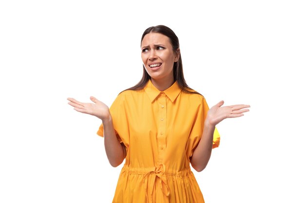 Photo young caucasian brunette woman with long hair dressed in a yellow summer dress is trying to remember