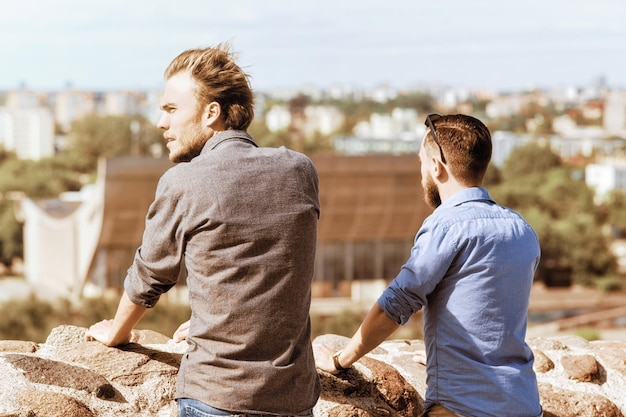 Young caucasian buddies look into distance at city skyline as travel and friendship concept