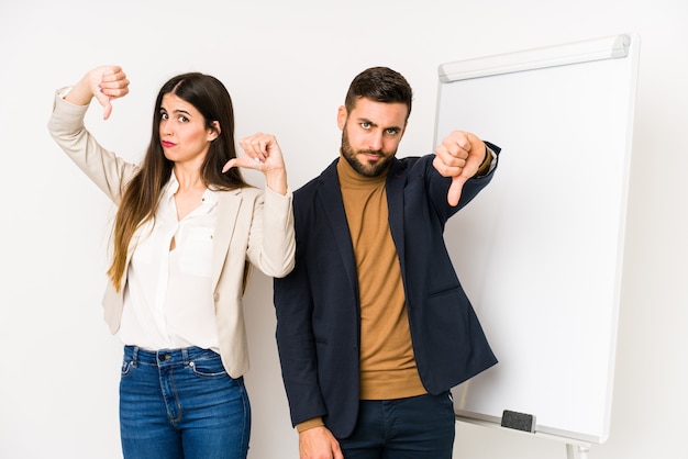 Young caucasian business couple showing thumb down and expressing dislike.