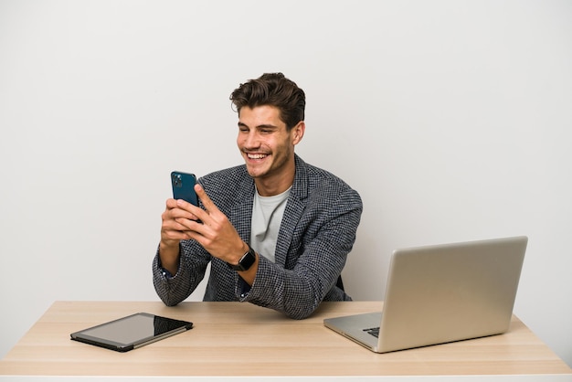Молодой кавказский предприниматель, работающий с ноутбуком, мобильным телефоном и планшетом