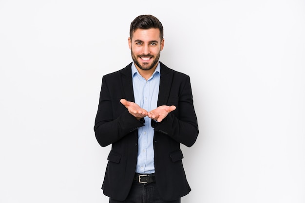 Young caucasian business man against a white wall holding something with palms