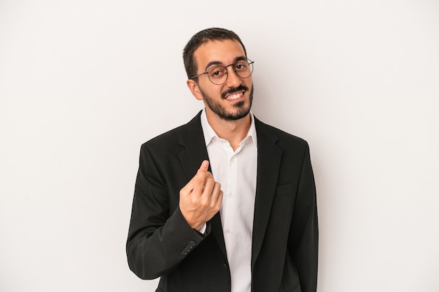 Young caucasian business man isolated on white background pointing with finger at you as if inviting come closer.