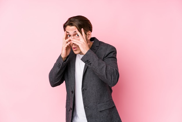 Photo young caucasian business man posing isolated blink through fingers frightened and nervous.