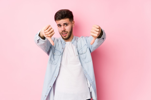 Young caucasian business man posing on white isolated showing thumb down and expressing dislike.< mixto >