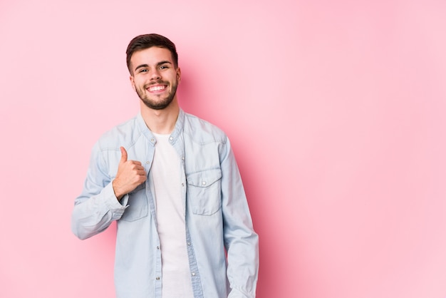 Young caucasian business man posing in a white wall isolated smiling and raising thumb up< mixto >