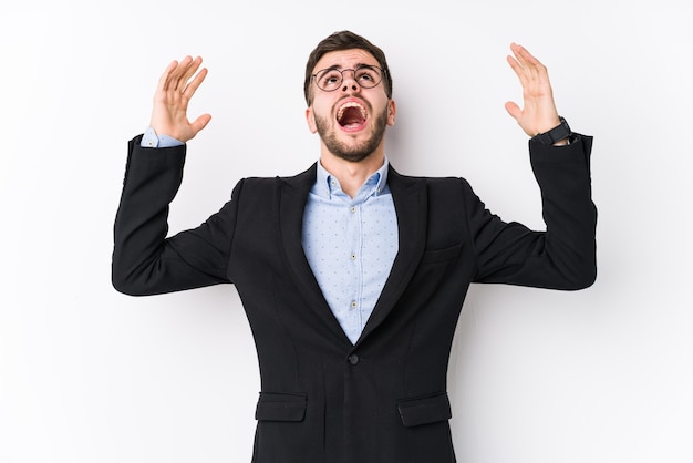 Young caucasian business man posing in a white Young caucasian business man screaming to the sky, looking up, frustrated.