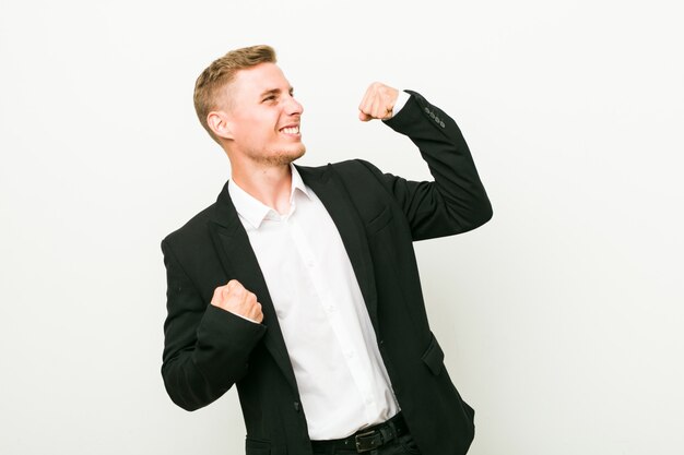 Young caucasian business man raising fist after a victory, winner concept.