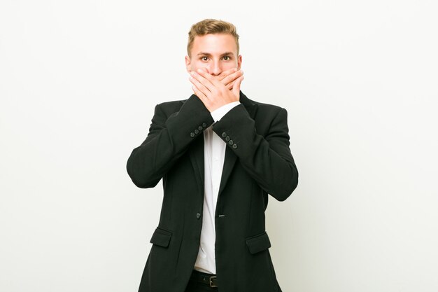 Young caucasian business man shocked covering mouth with hands.