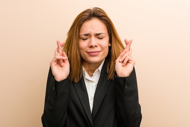 Young caucasian business woman crossing fingers for having luck