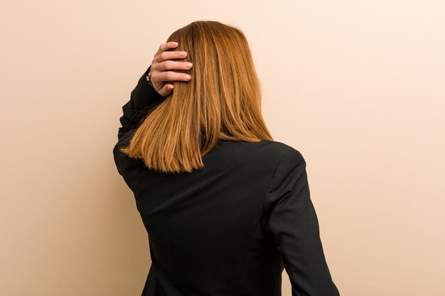 Young caucasian business woman from behind thinking about something.