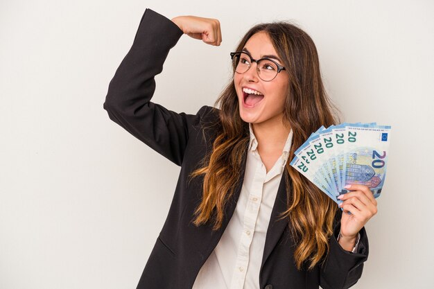 Young caucasian business woman holding banknotes isolated on white background raising fist after a victory, winner concept.